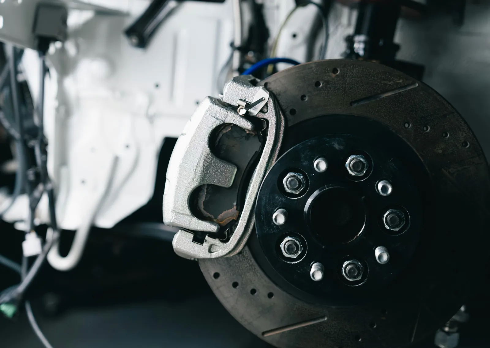 Drilled brake rotor and caliper on a car with the wheel removed