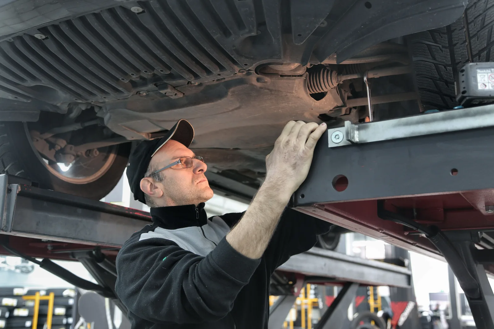 ASE-certified technician inspecting vehicle suspension on a lift